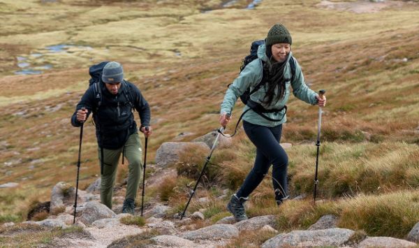 Two walkers climbing a gradient hill using walking poles.